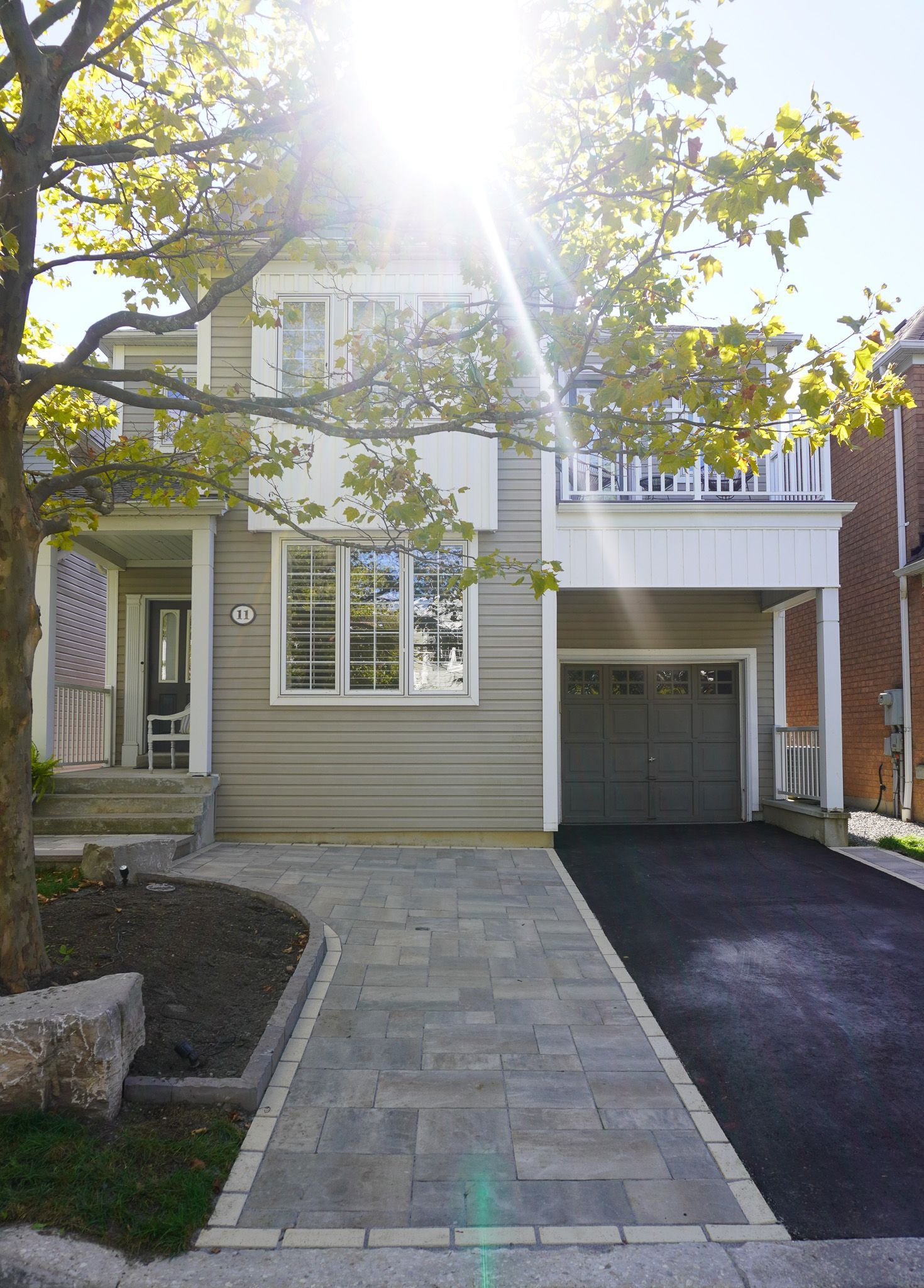 The sun is shining through the trees in front of a house