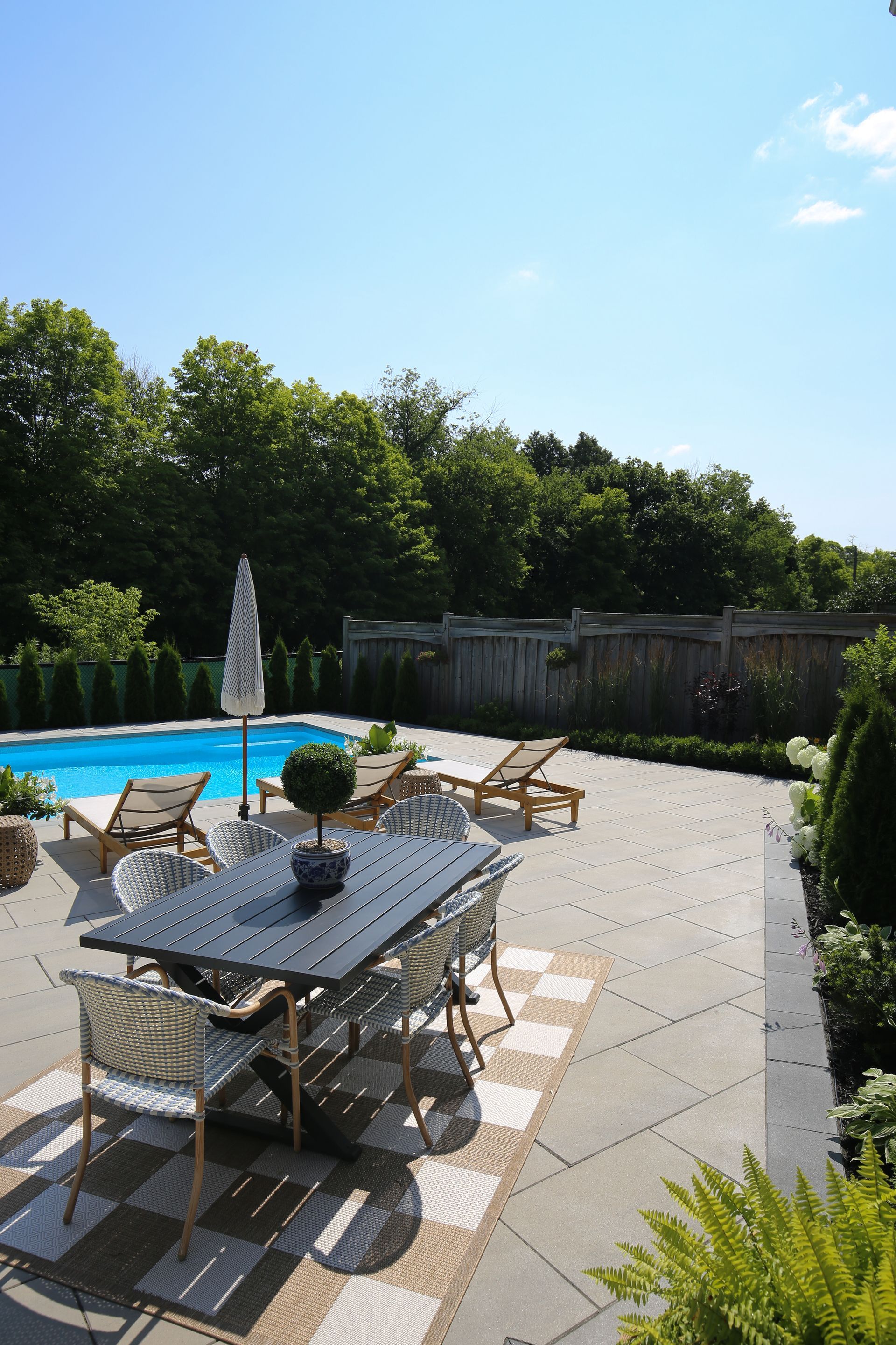 A patio with a table and chairs next to a pool.