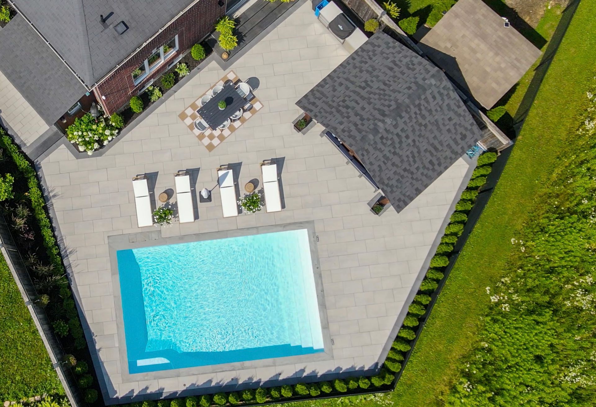 An aerial view of a swimming pool with a house in the background.