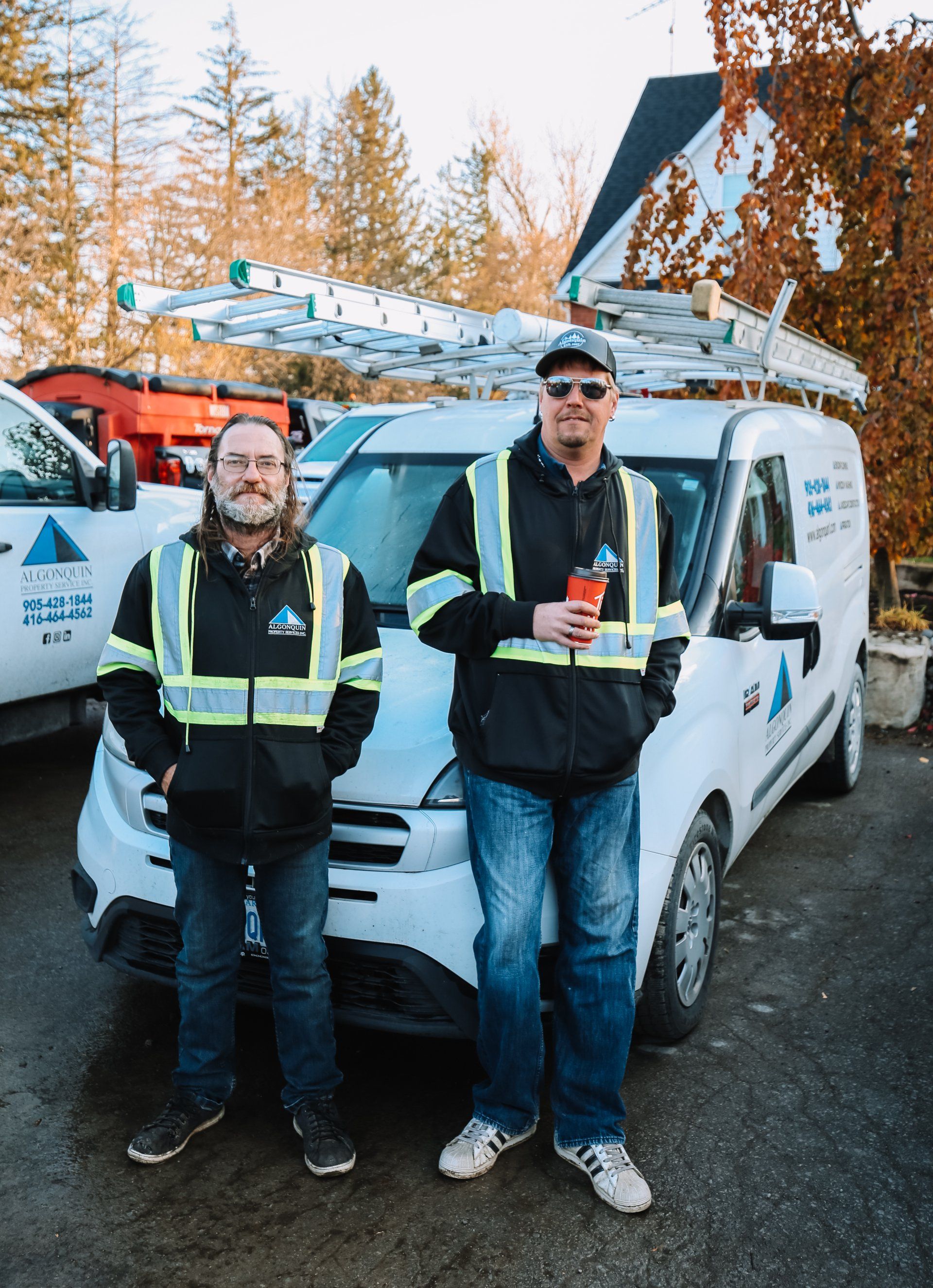 Two men are standing next to each other in front of a van.