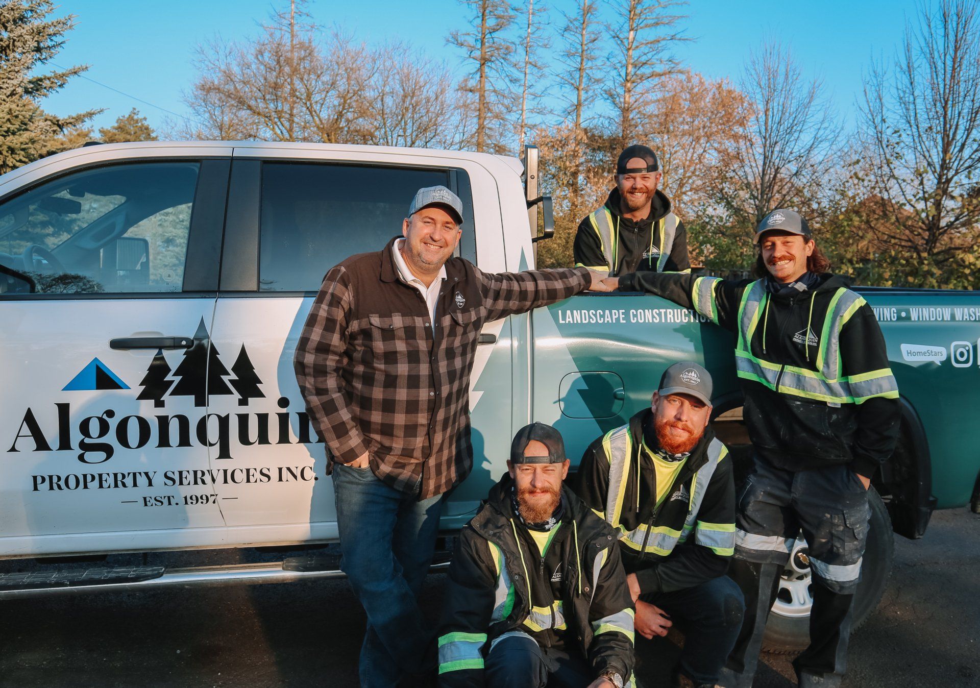 A group of men are posing for a picture in front of a truck.
