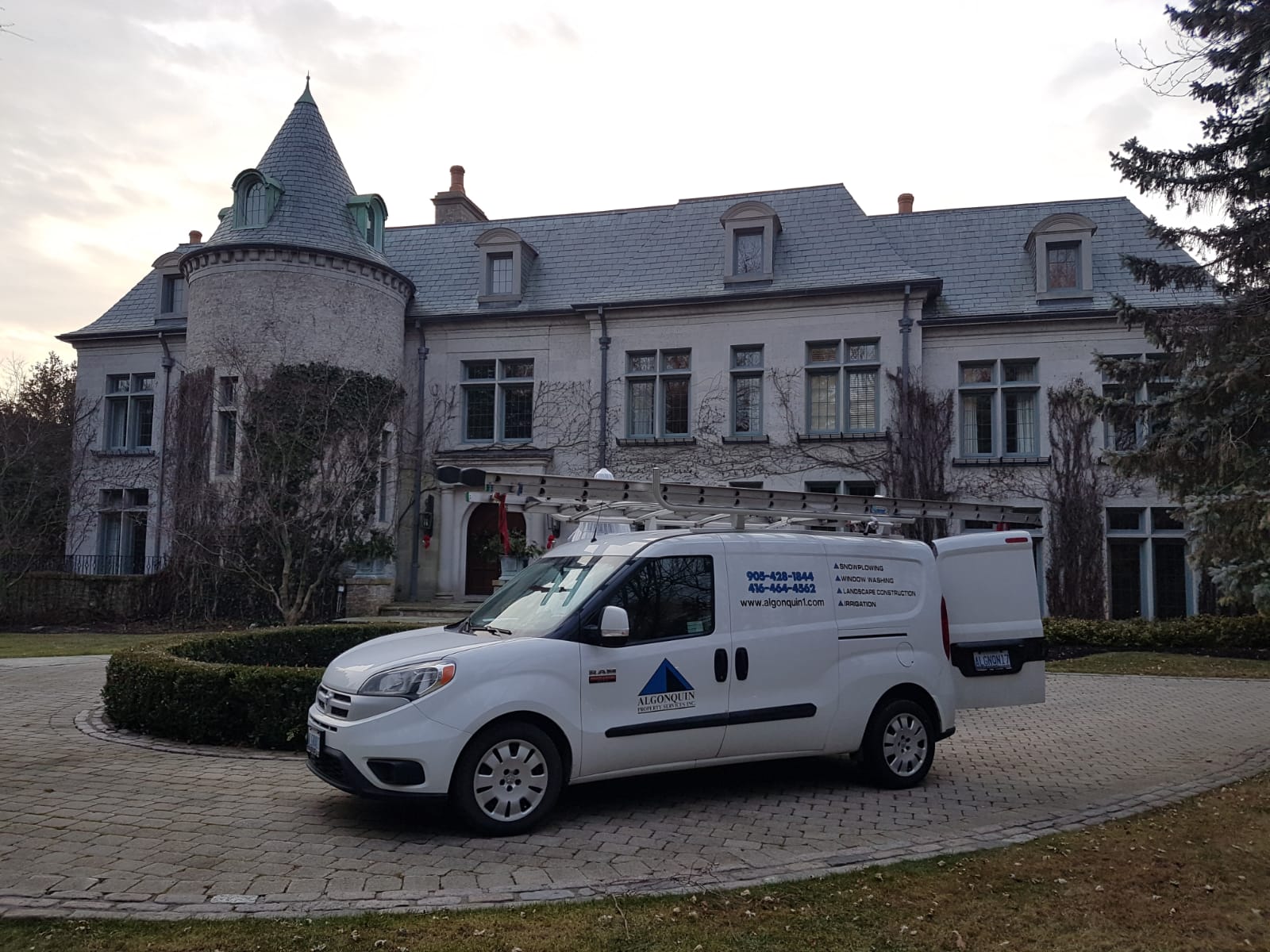 A white van is parked in front of a large white building