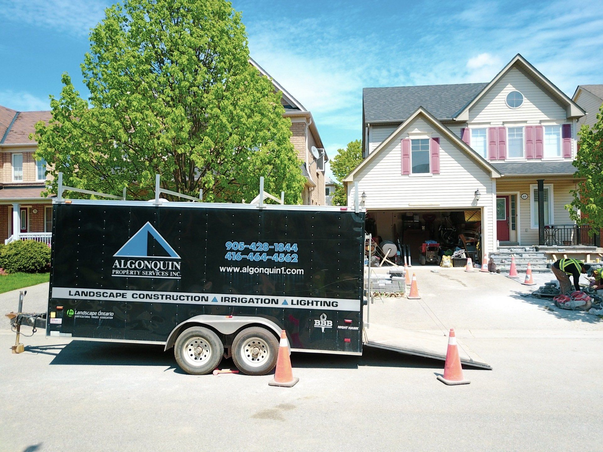 A black trailer with a triangle on it is parked in front of a house