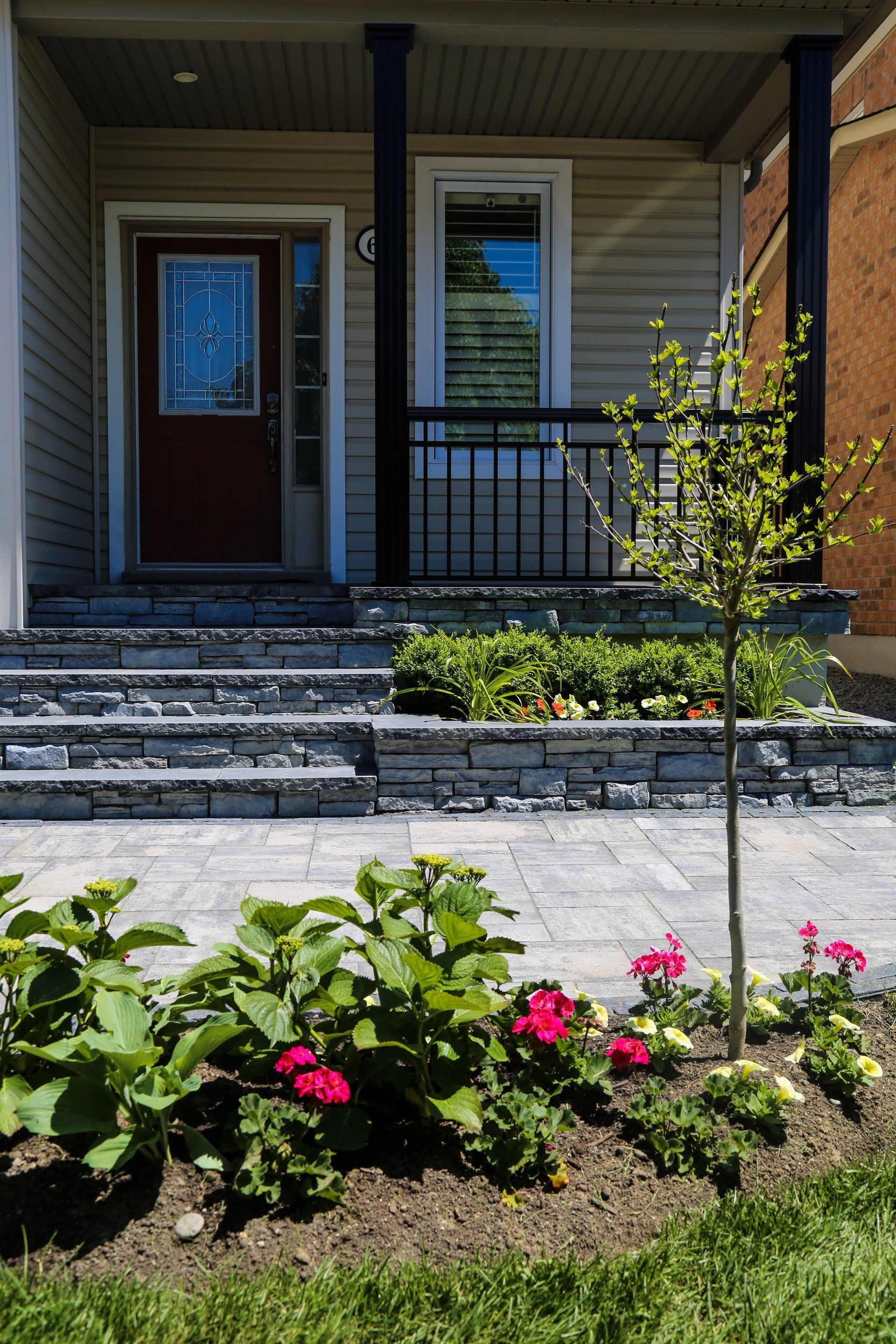 The front of a house with a porch and flowers in front of it.