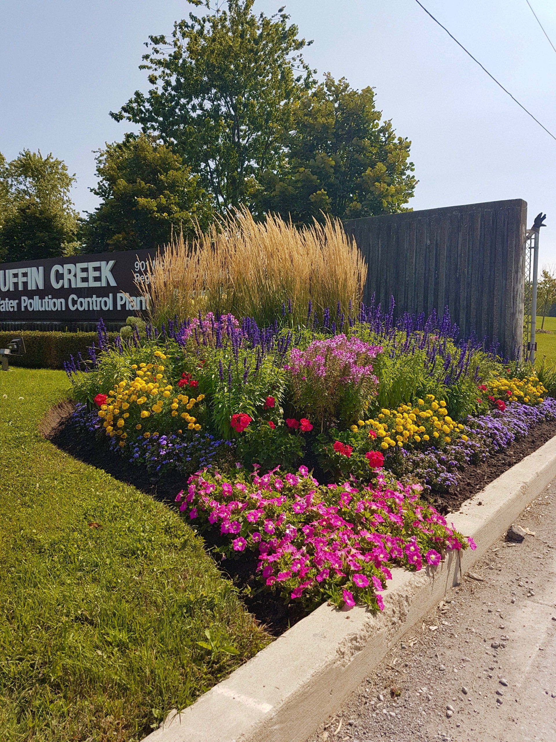 A sign for a park with flowers in front of it