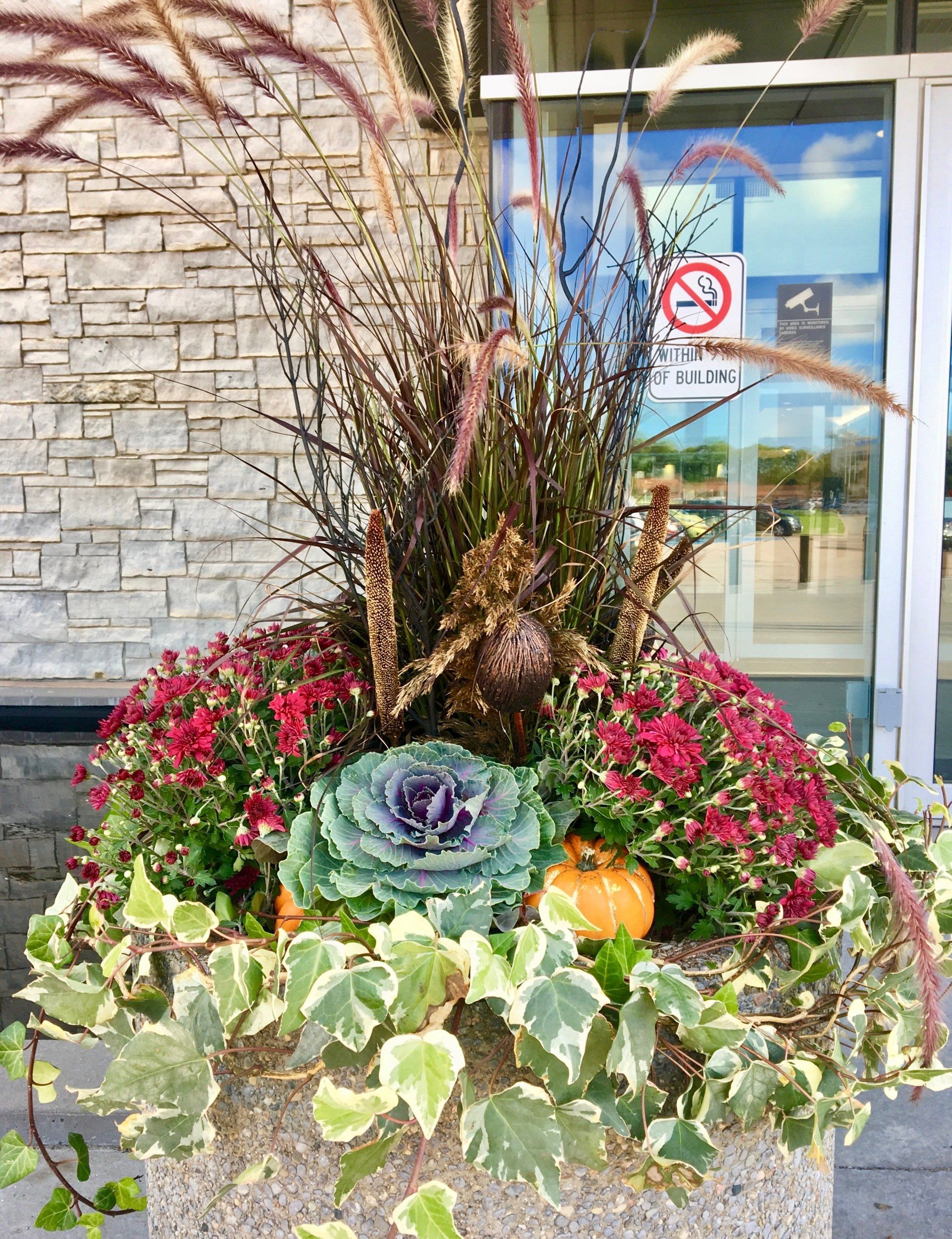 A planter filled with flowers and plants is in front of a building.