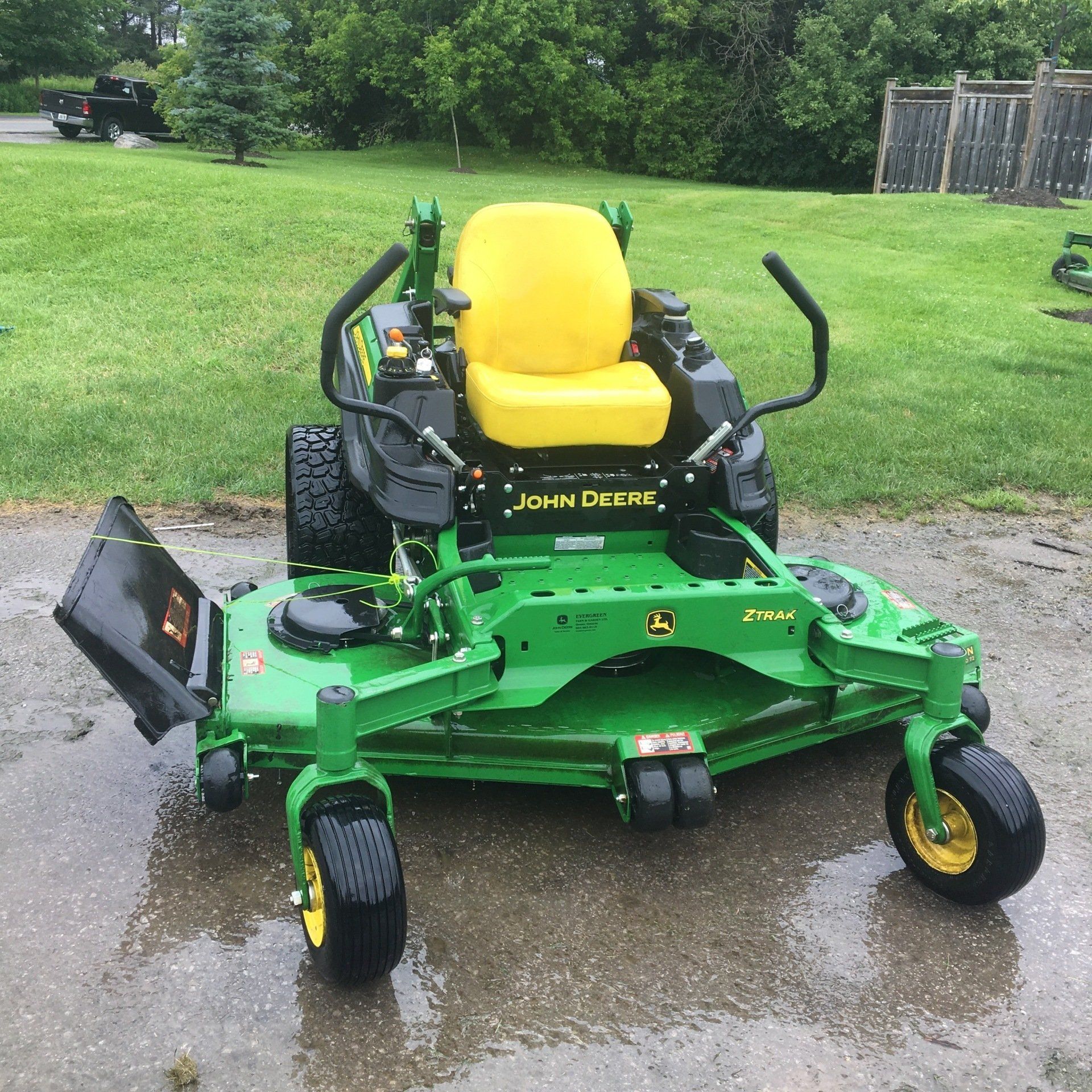 A green john deere lawn mower with a yellow seat