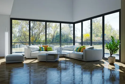 Modern living room with white sectional sofa, large windows, and a plant.