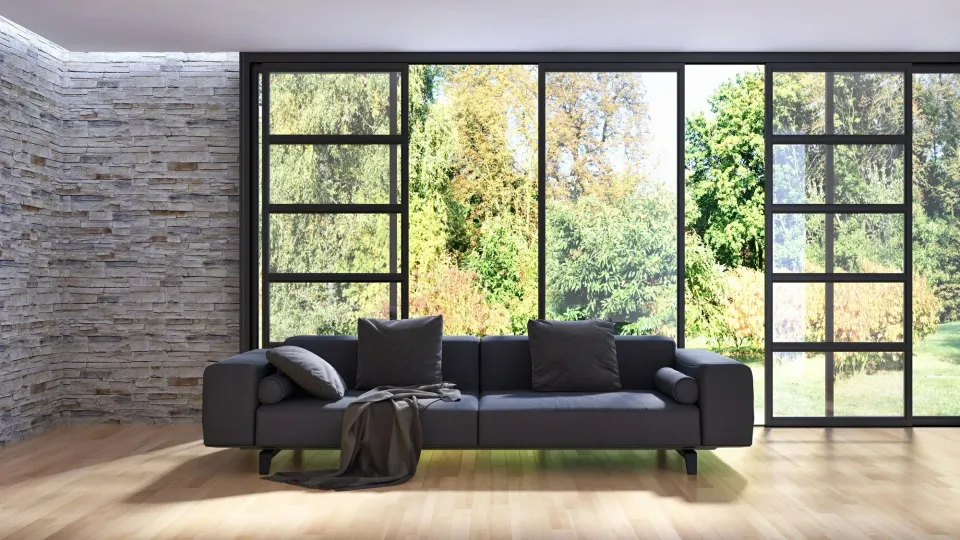 Modern living room with black sofa, large windows, and natural scenery.