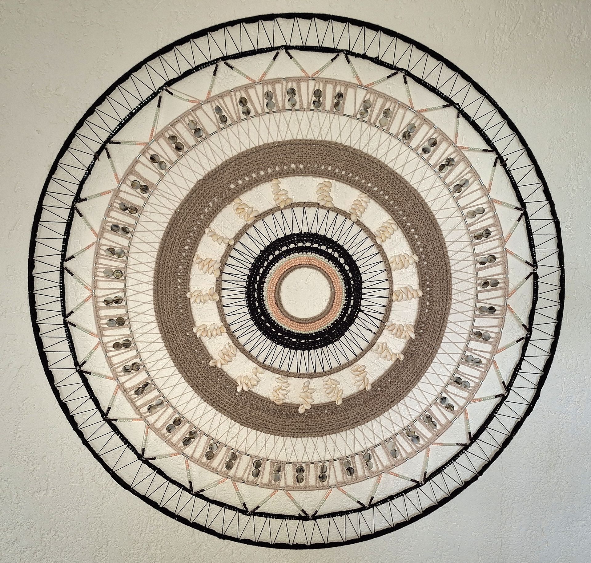 Muurkunst met een cirkelvormige textuur, concentrische ringen in beige, bruin en zwart. Gemaakt door Lisette Hoppener