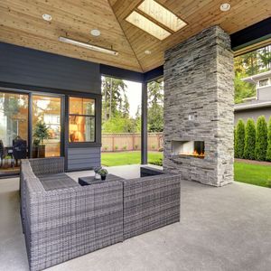 A patio with wicker furniture and a stone fireplace