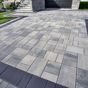 A gray and black brick driveway with a black border