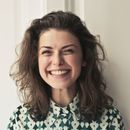 A woman wearing a green and white shirt is smiling