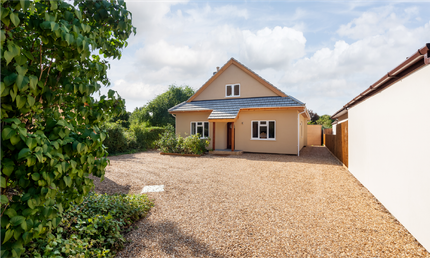 A house with a gravel driveway in front of it.