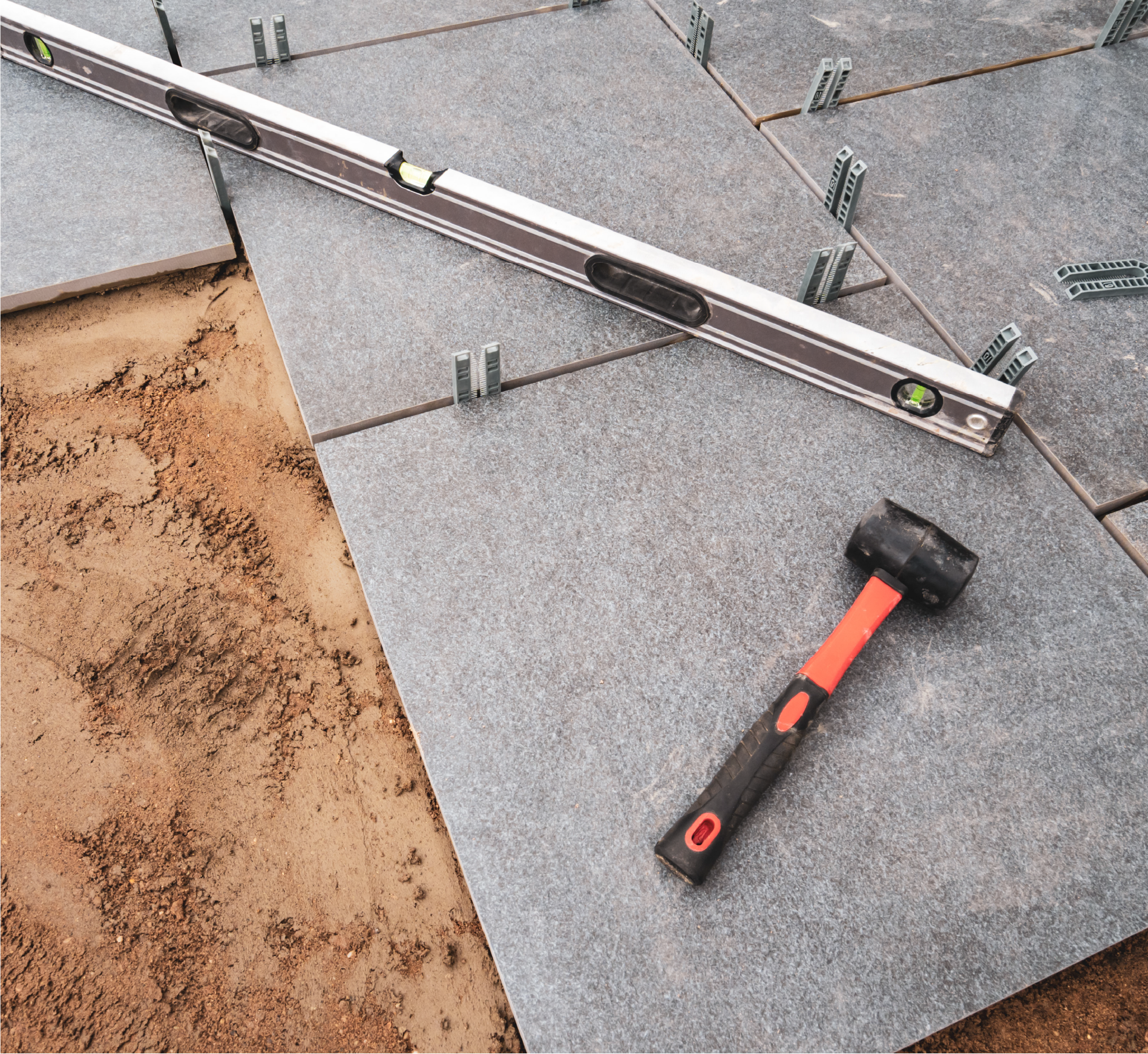 A hammer and a level are sitting on top of a tile floor.