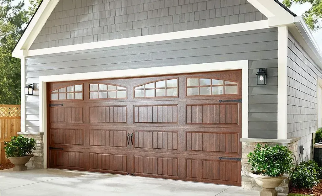 A garage with a wooden door and a gray siding