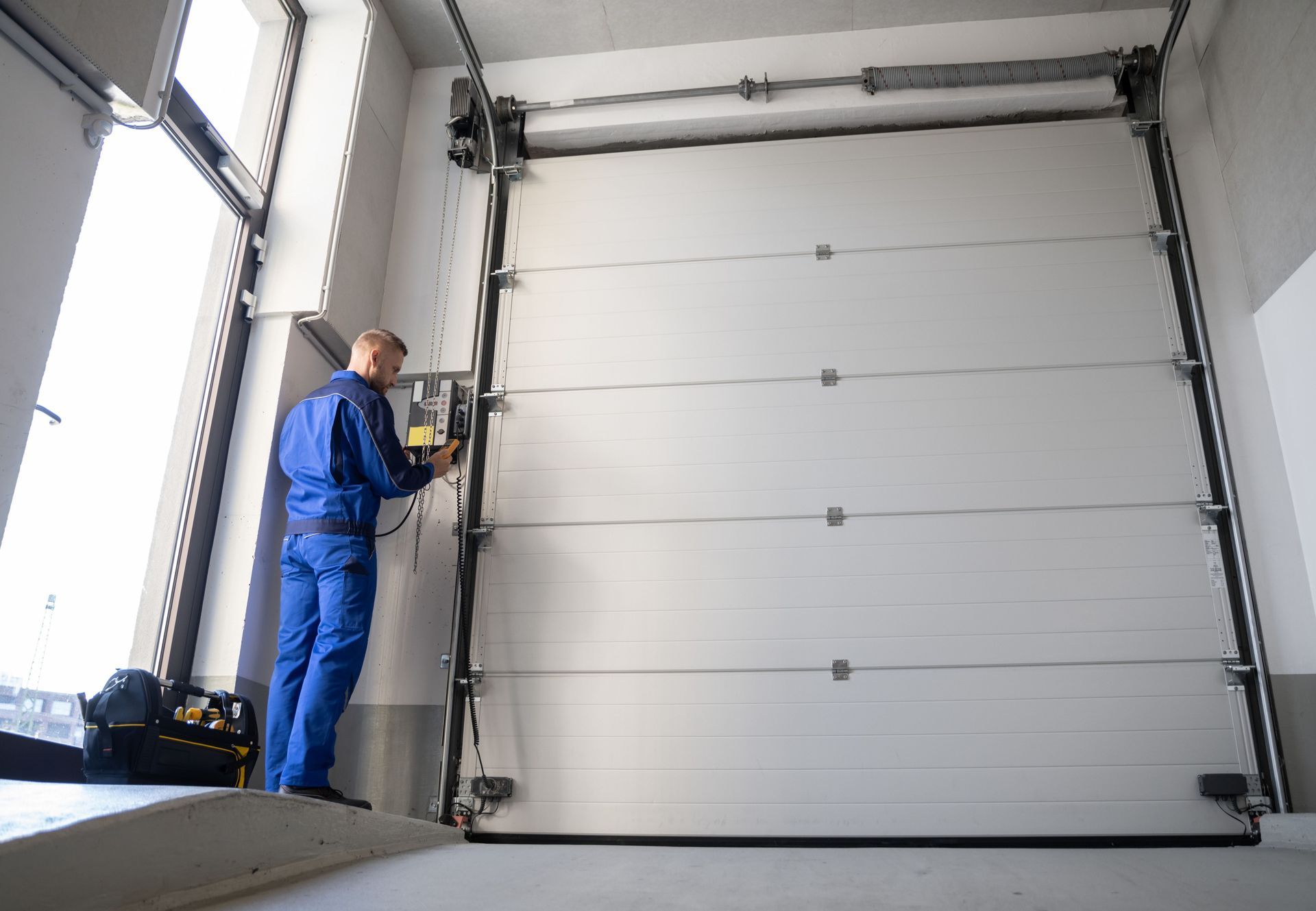 A man is working on a garage door in a garage.