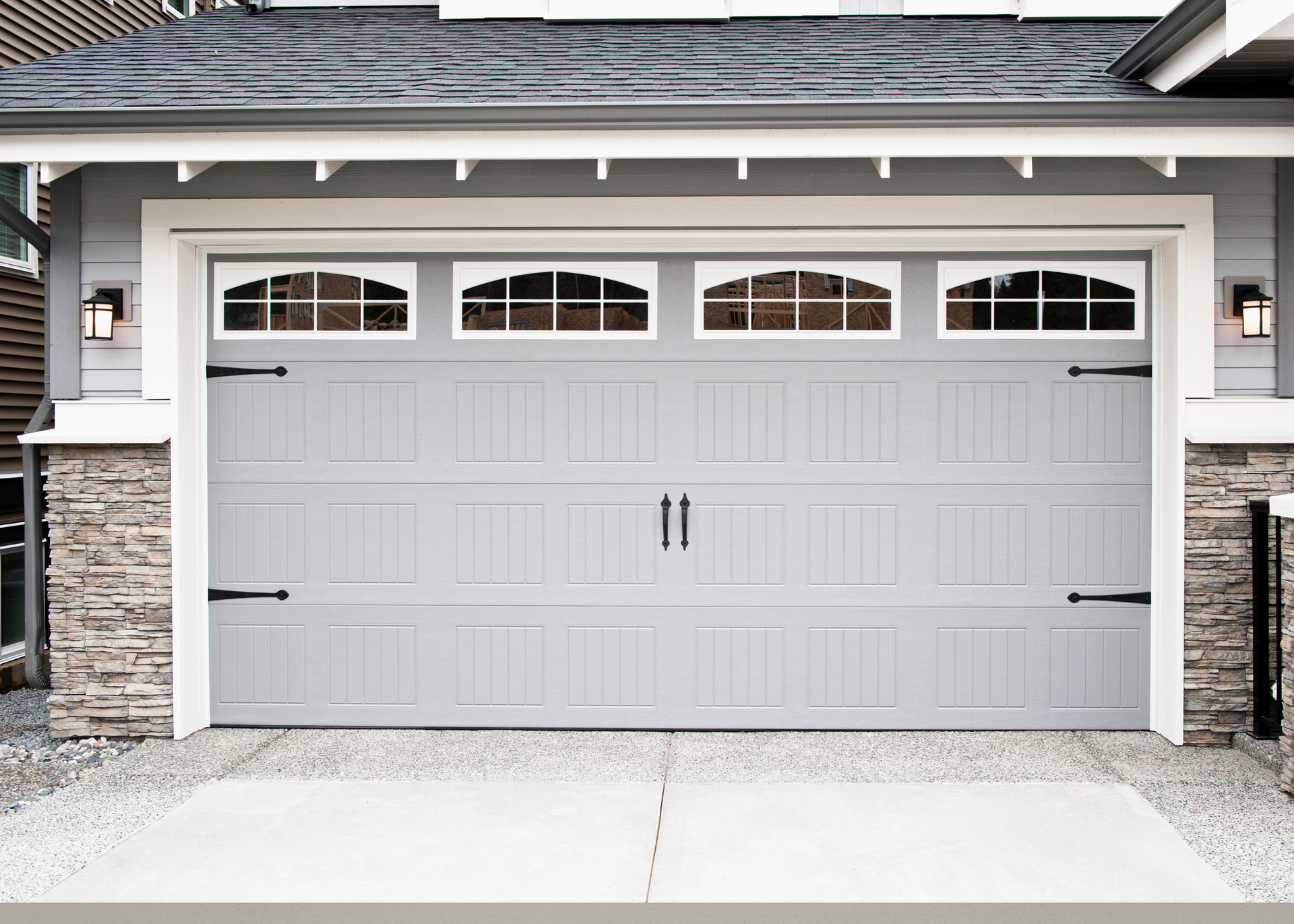 A large gray garage door is sitting in front of a house.