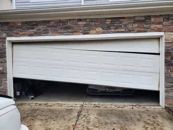 A car is parked in a garage with a broken garage door.