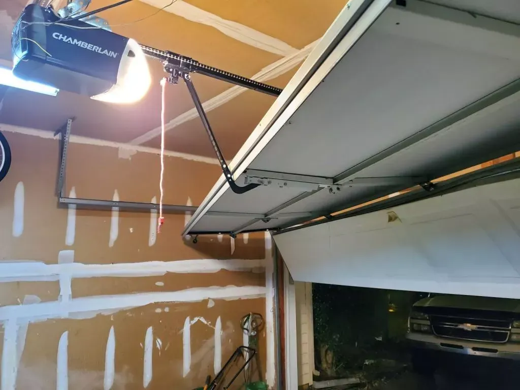 A garage door opener is hanging from the ceiling of a garage.