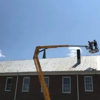 A Man is working on the Roof of a Building with a Crane - Chester, VA - A. Townsley Contracting