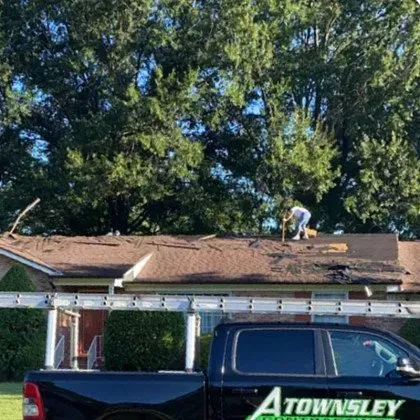 A Truck is parked in Front of a House with a Man working on the Roof - Chester, VA - A. Townsley Contracting