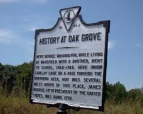 Historical marker titled History at Oak Grove in a grassy field under a blue sky.