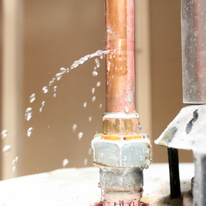 A close up of a copper pipe with water coming out of it.