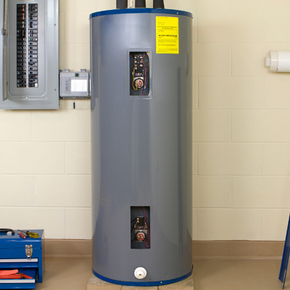 A gray water heater is sitting in a garage next to a toolbox.