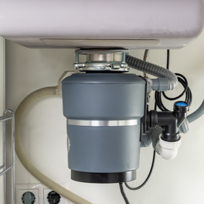 A garbage disposal is under a sink in a kitchen.