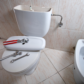 A toilet and bidet in a bathroom with tools on the seat