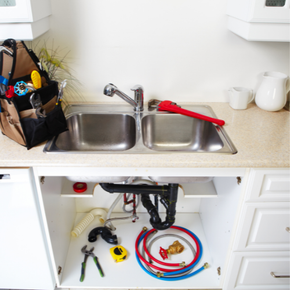 A kitchen sink with tools and a tool bag on the counter