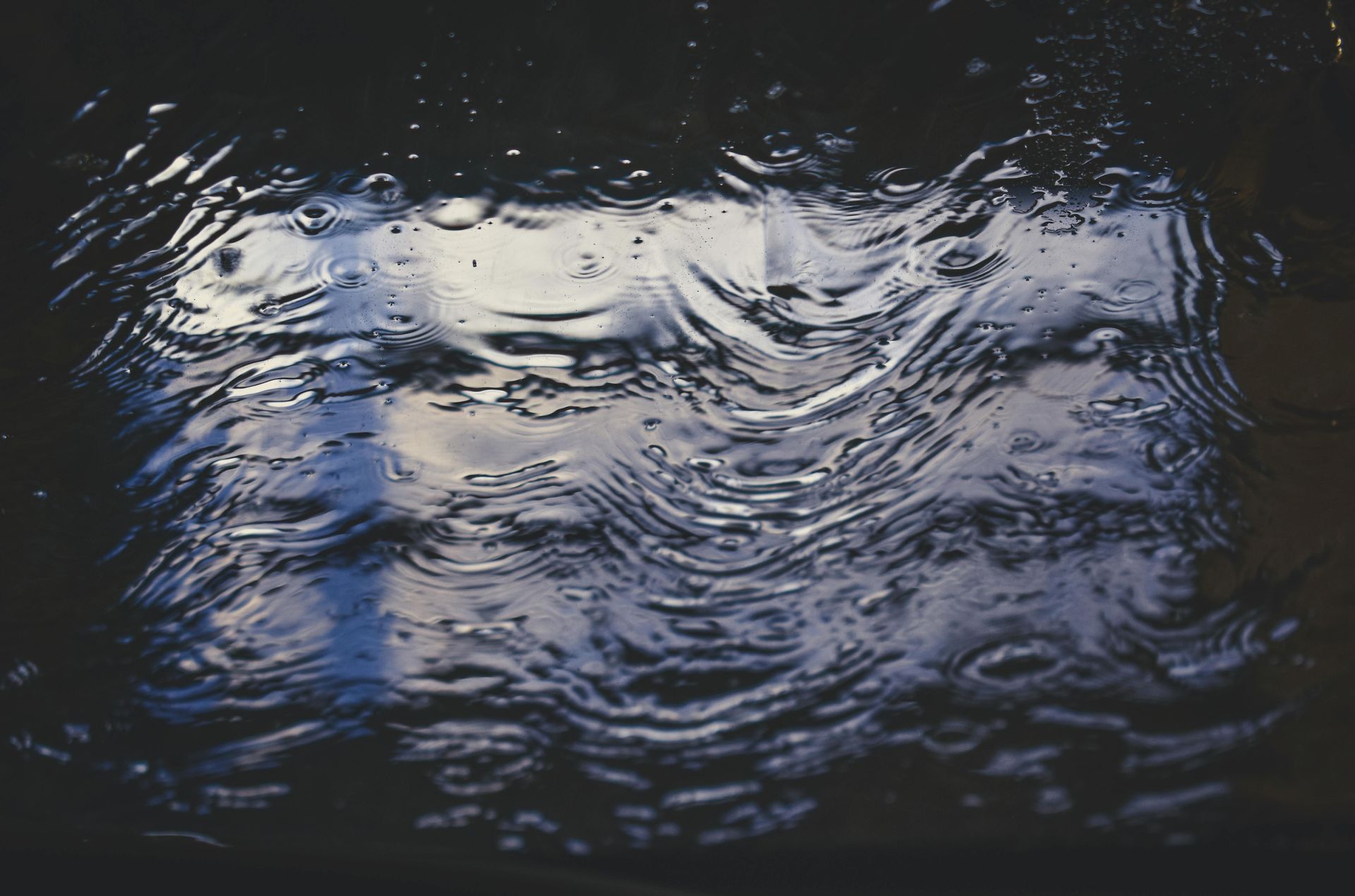 A close up of a puddle of water with a reflection of a person in it.