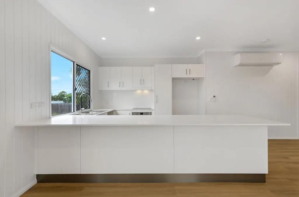 An Empty Kitchen With White Cabinets and a Large Island — Drawing Works In Townsville City, QLD
