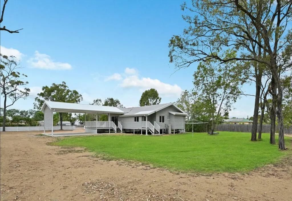 A White House With a Covered Porch is Surrounded by Trees and Grass — Drawing Works In Townsville City, QLD