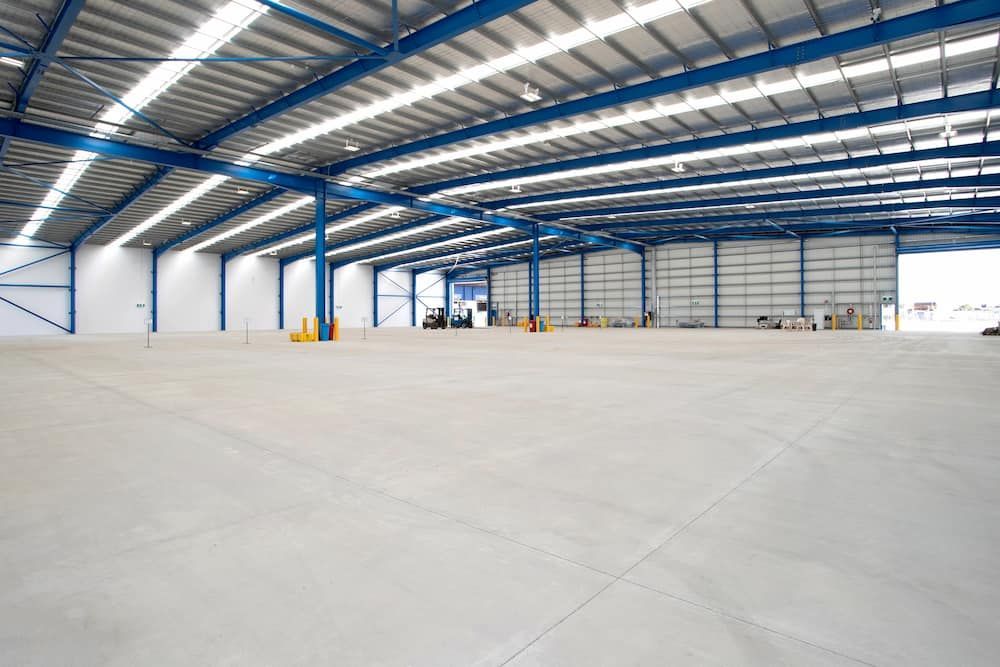 An Empty Warehouse With a Blue Roof and a Concrete Floor — Drawing Works In Townsville City, QLD
