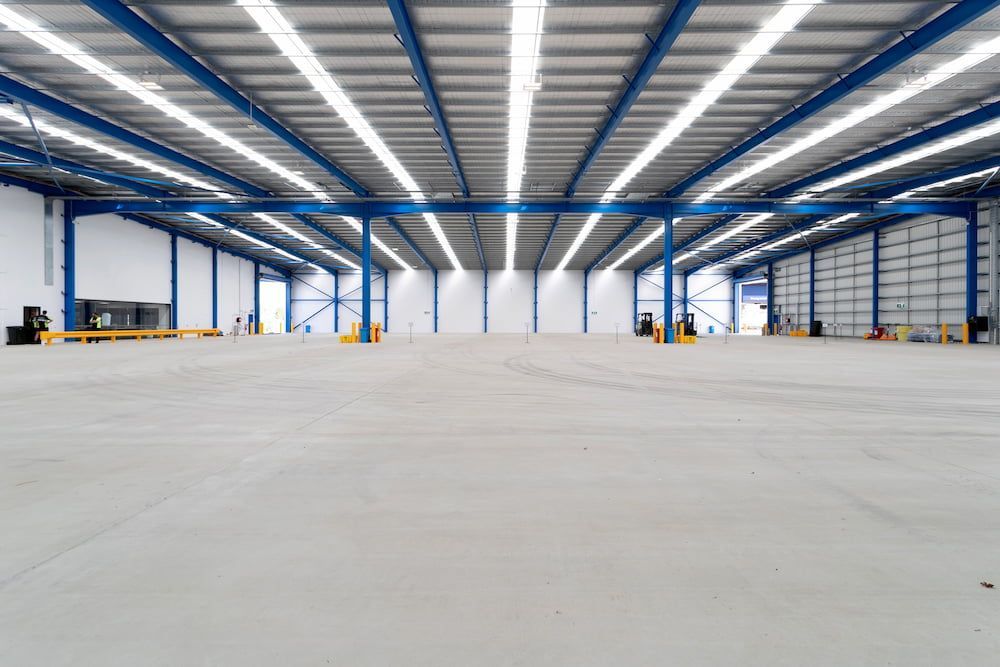 A Large Empty Warehouse With a Blue Roof and a Concrete Floor  — Drawing Works In Townsville City, QLD