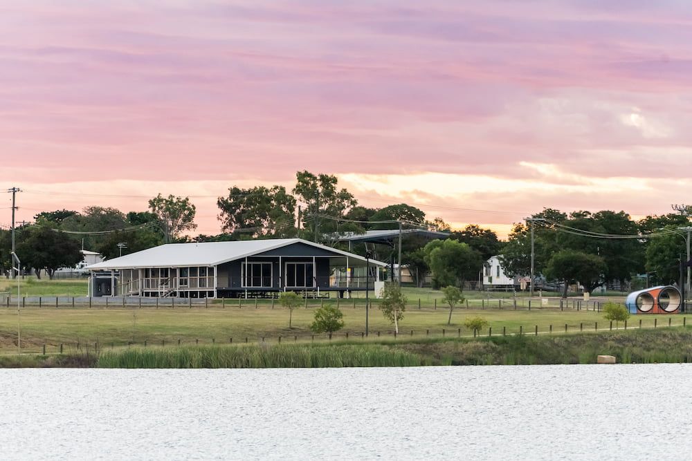 A House is Sitting on the Shore of a Lake at Sunset — Drawing Works In Townsville City, QLD