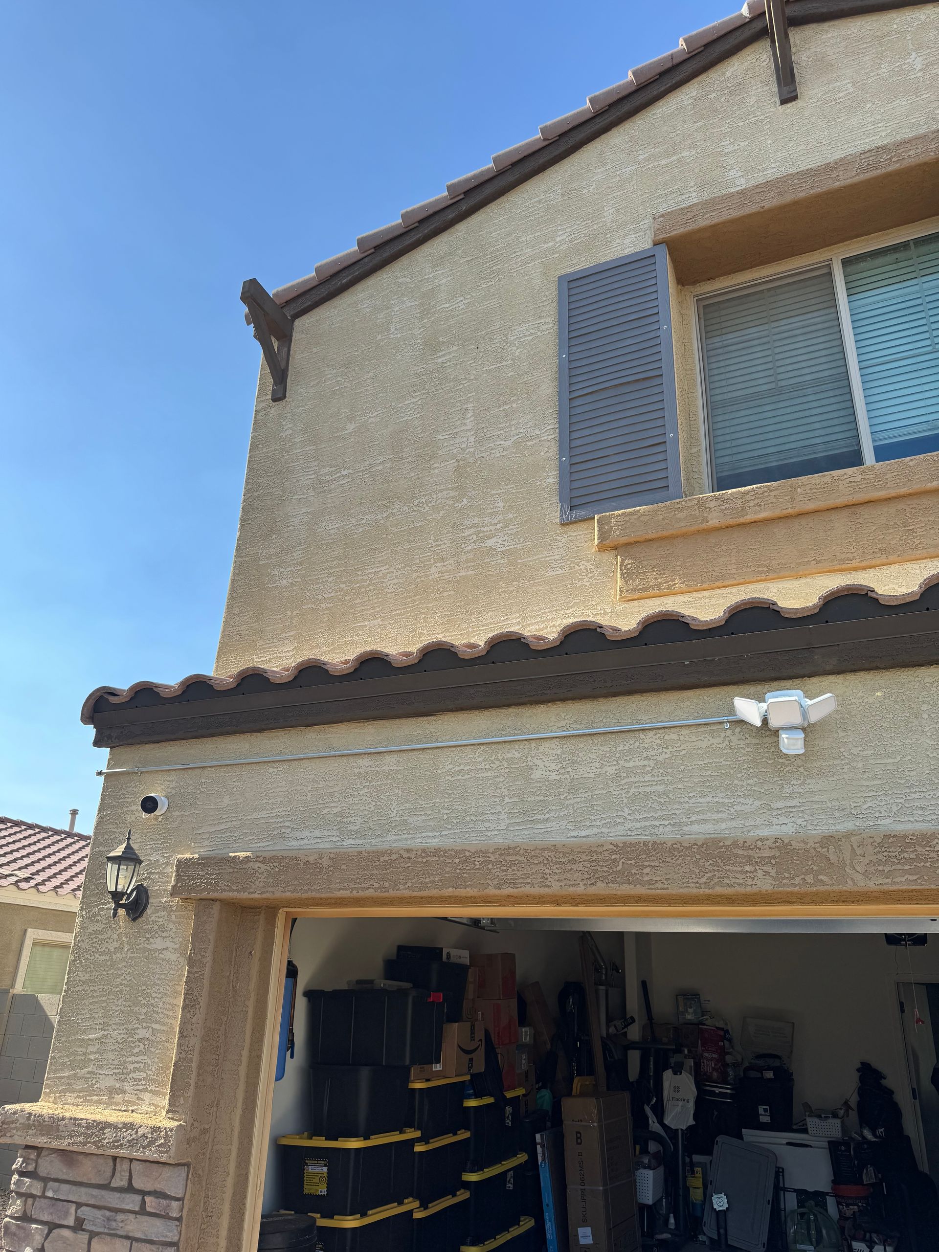 Beige stucco house with brown trim and a garage, blue sky.