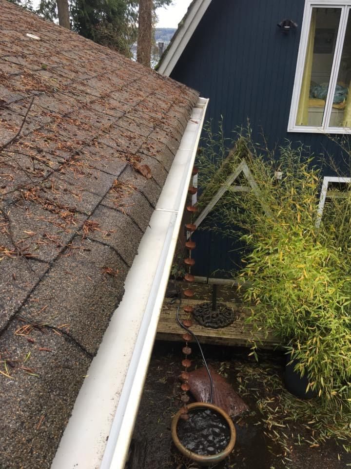 A white gutter is hanging from the roof of a house.