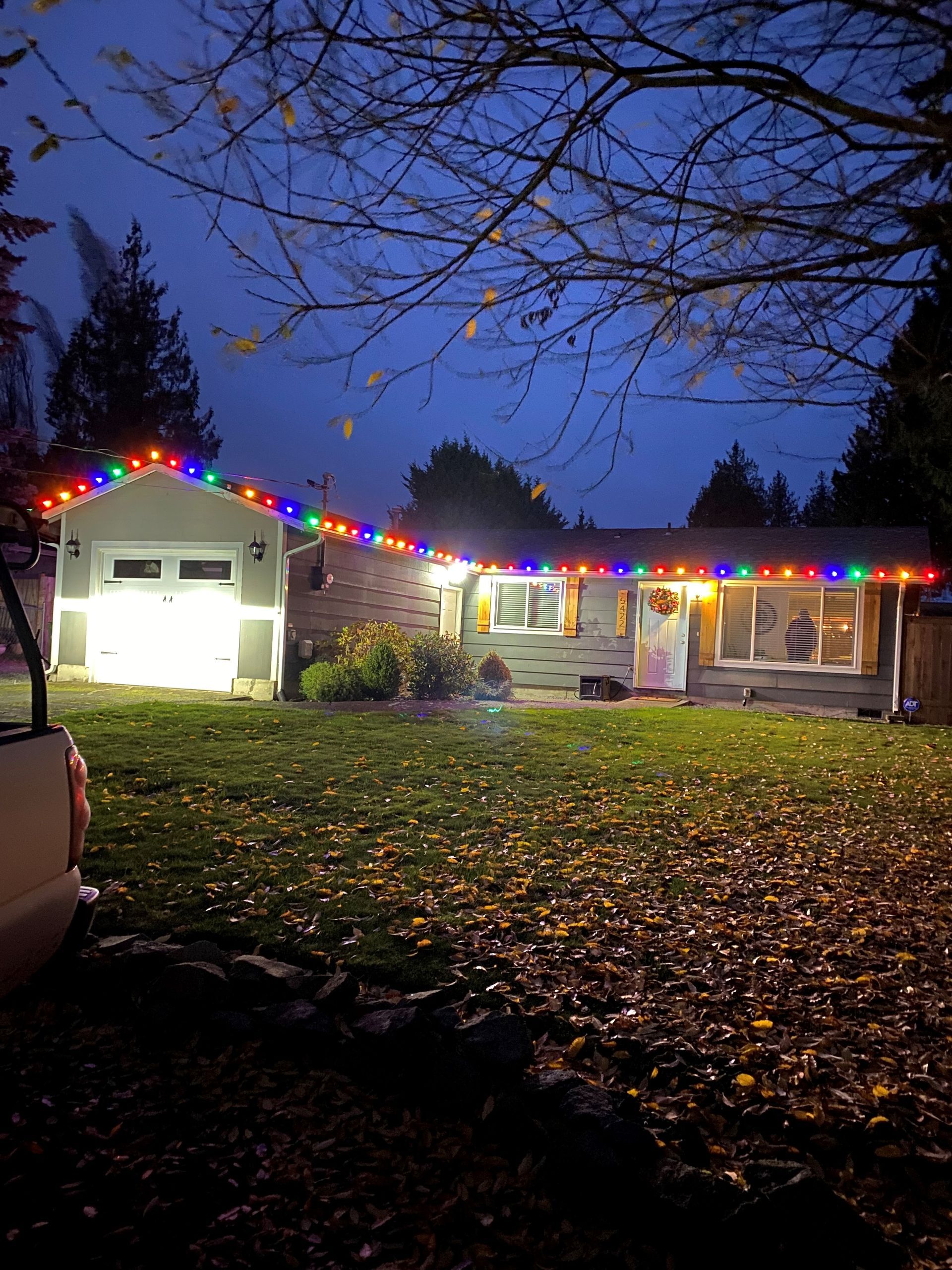 A house is decorated with christmas lights and a truck is parked in front of it.