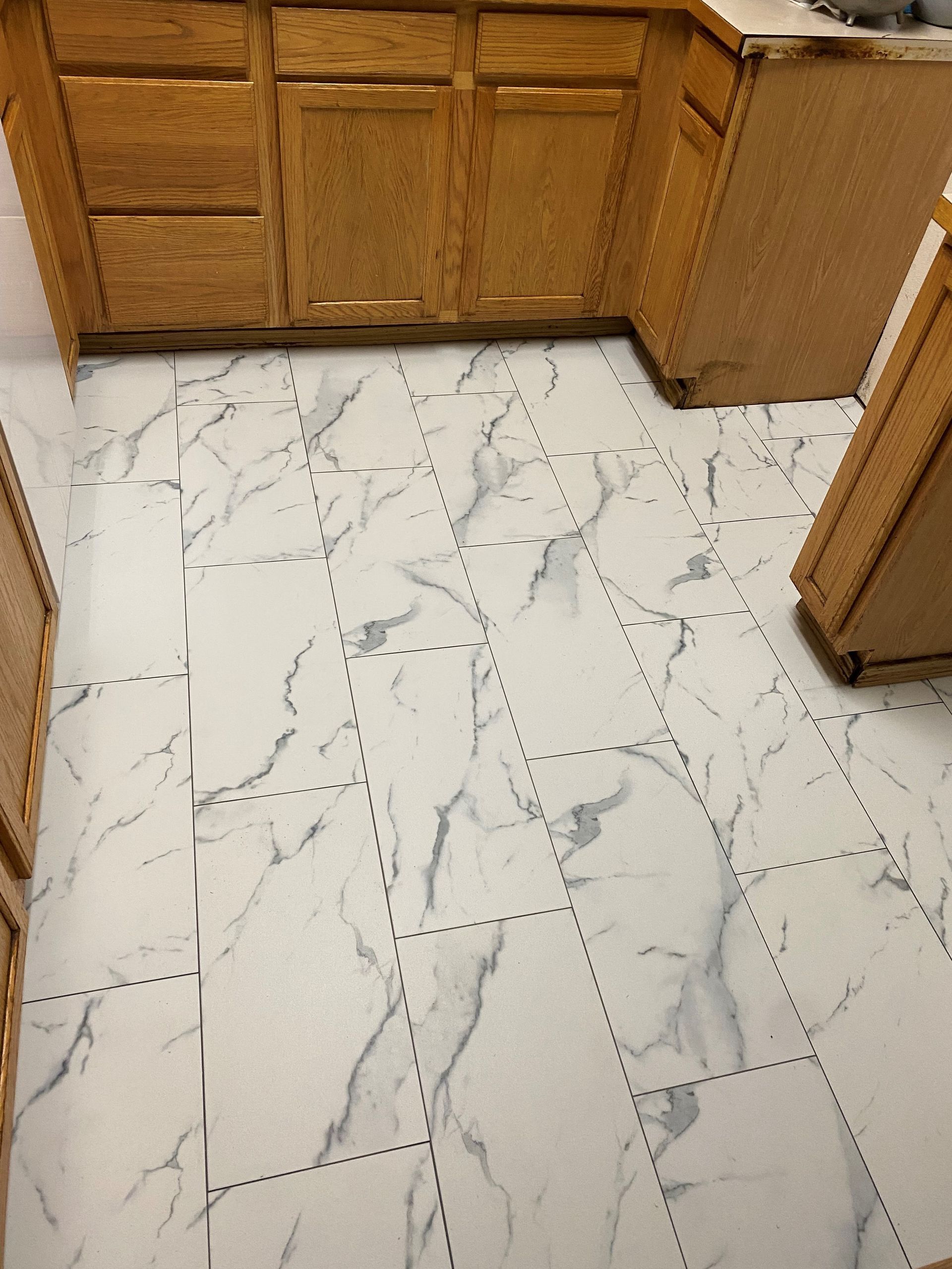 A kitchen with marble floor tiles and wooden cabinets.