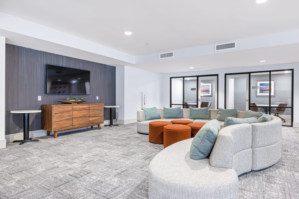 a room with a couch, ottomans, and a flat-screen tv at Marquis at Chandler in Chandler, AZ.