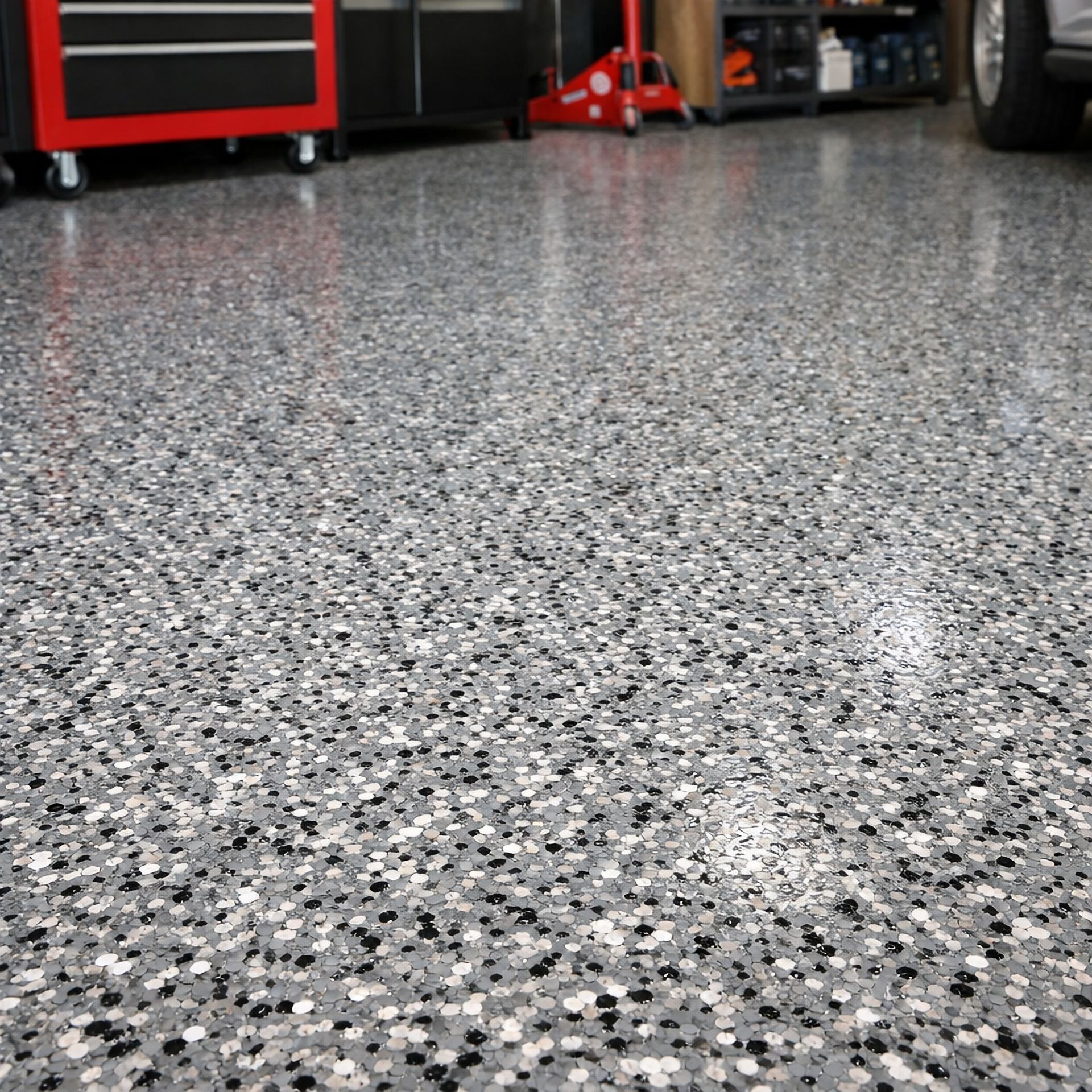 Speckled gray garage floor with red tool cabinets in the background