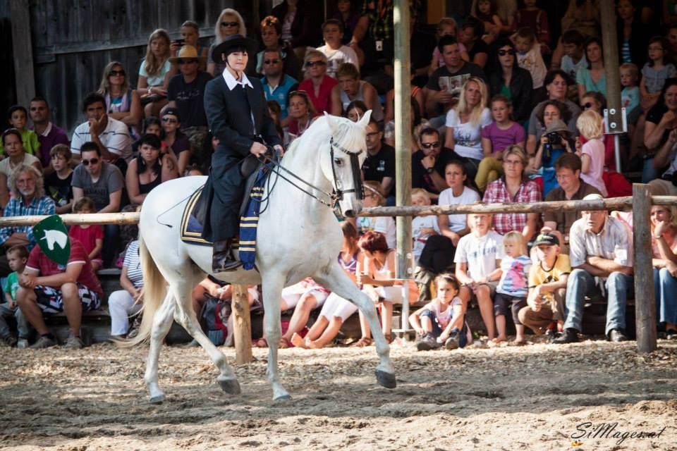 eine Frau reitet auf einem weißen Pferd vor einem Publikum