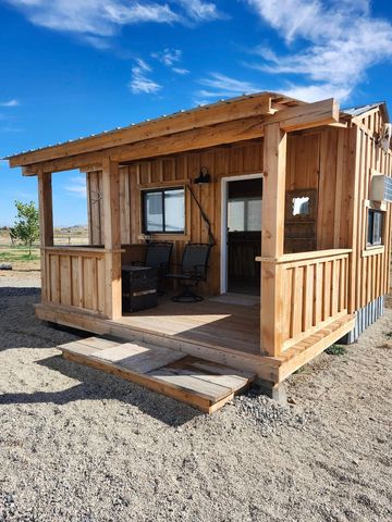 A small wooden cabin with a porch and rocking chairs