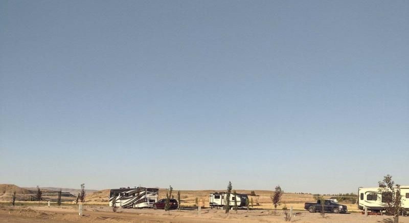A row of rvs parked in a desert with a blue sky in the background.