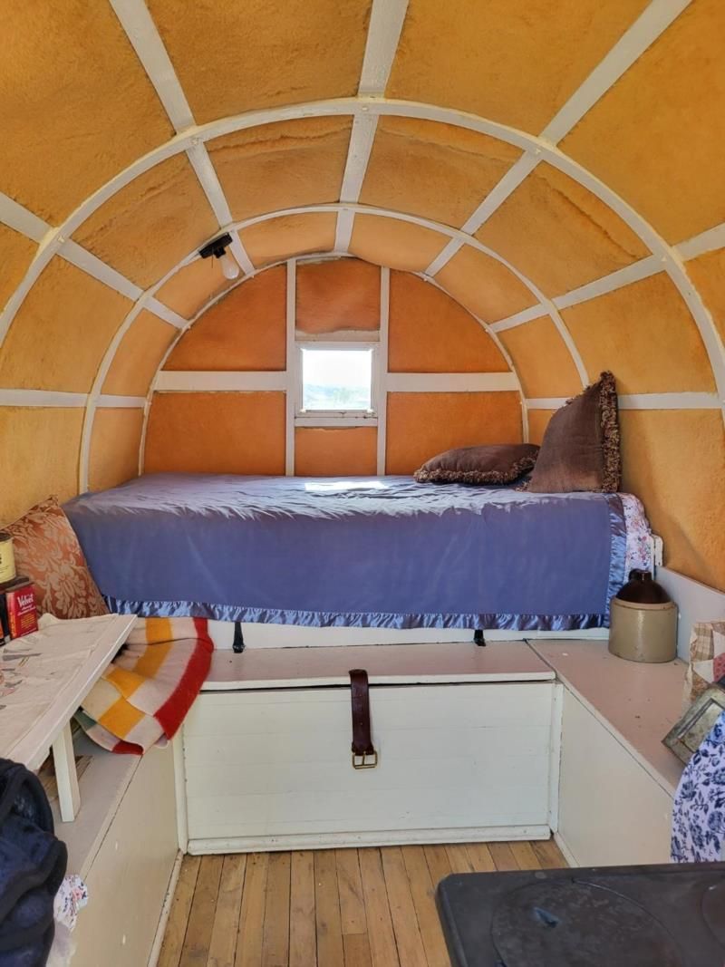 The inside of a wagon with a bed and a window