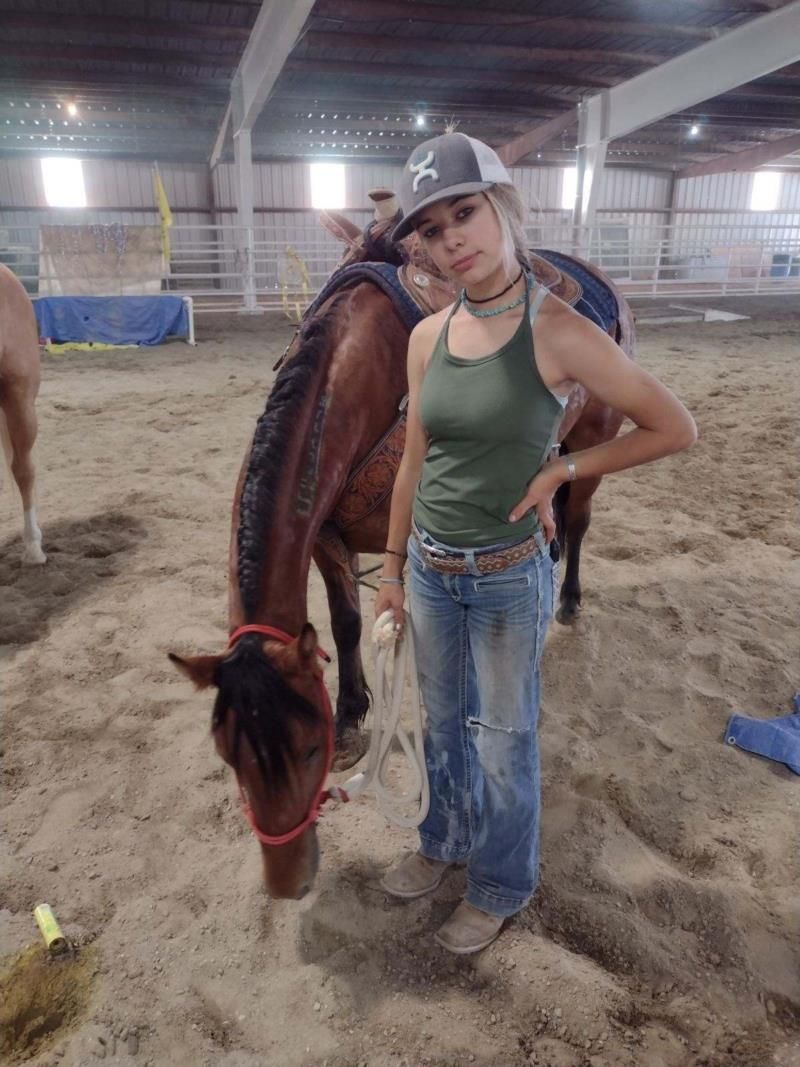 A woman is standing next to a horse in a stable.