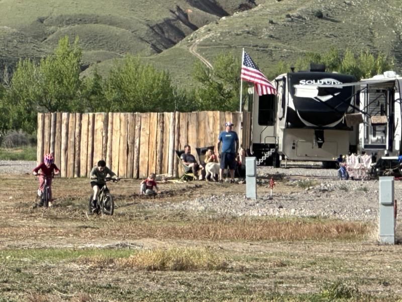 A group of people riding bikes in a field with a rv in the background